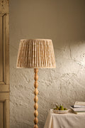 Balcomie pleated lampshade in Oat on a wooden floor lamp in a warm neutral interior