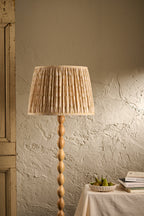 Balcomie pleated lampshade in Oat on a wooden floor lamp in a warm neutral interior