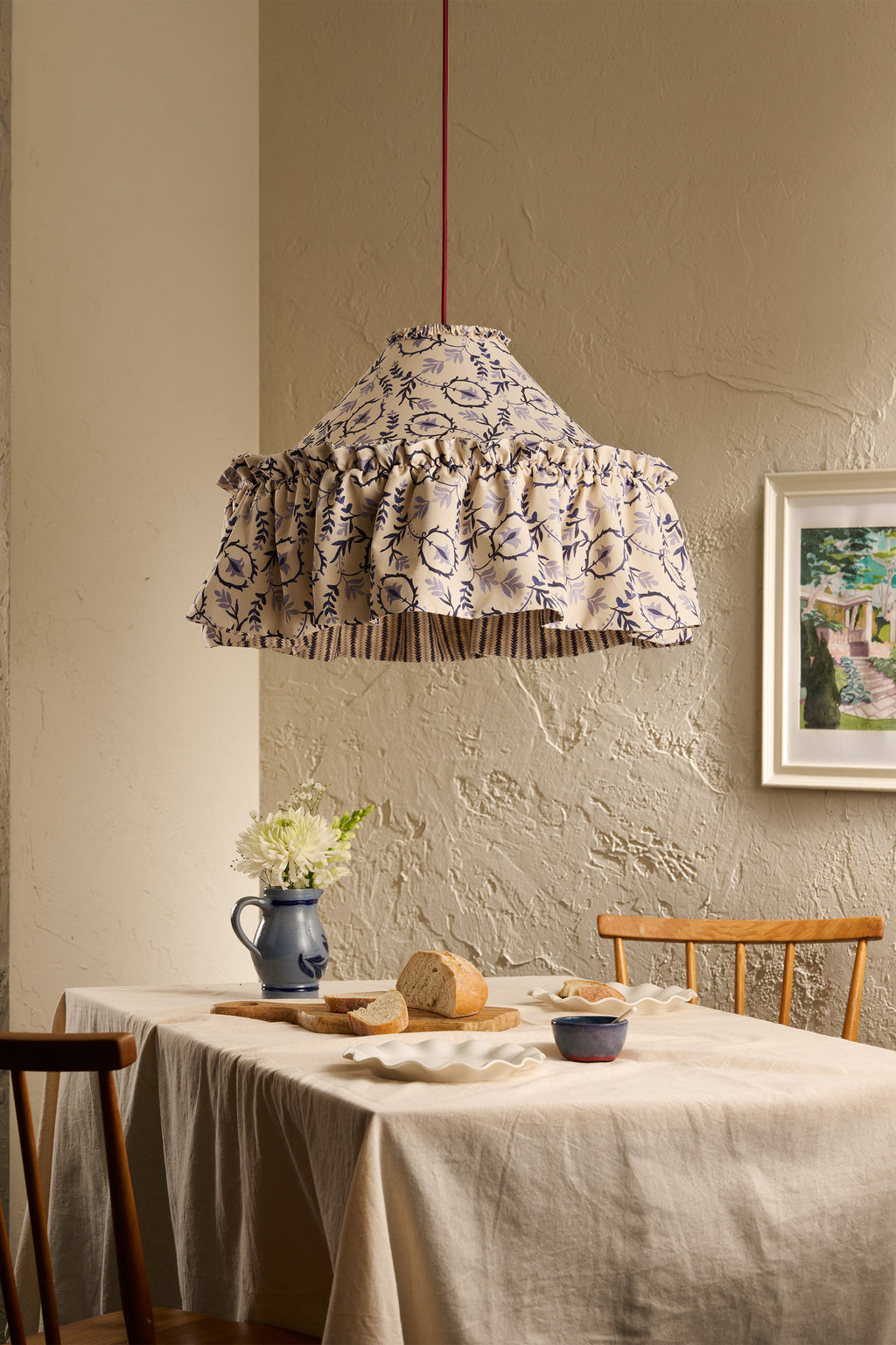 Daunder Ruffle Statement Lampshade in Indigo with contrasting striped lining hanging above a dining table