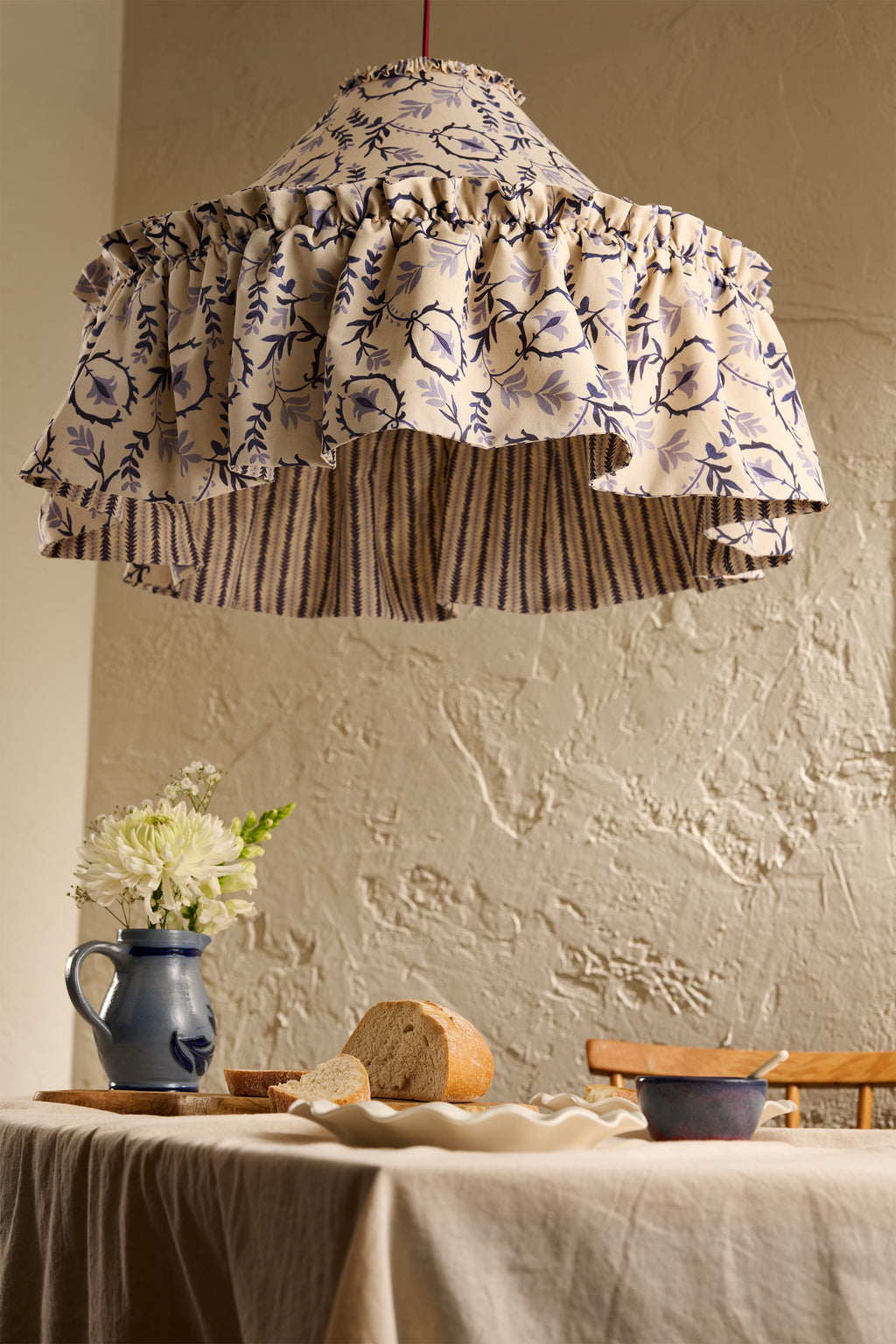Daunder Indigo Ruffle Statement Lampshade in Indigo with contrasting striped lining hanging above a dining table
