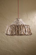 Daunder Ruffle Statement Lampshade in Indigo with frilled skirt and contrast lining hanging in front of a textured wall