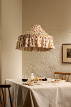 Daunder Ruffle Statement Lampshade in Ochre and Merlot hanging above a dining table in a warm neutral interior