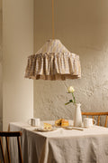 Ellis Ruffle Statement Lampshade in Dusty Sky & Ochre hanging above a dining table, showing the contrasting geometric lining