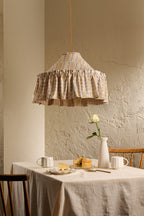 Ellis Ruffle Statement Lampshade in Dusty Sky & Ochre hanging above a dining table, showing the contrasting geometric lining