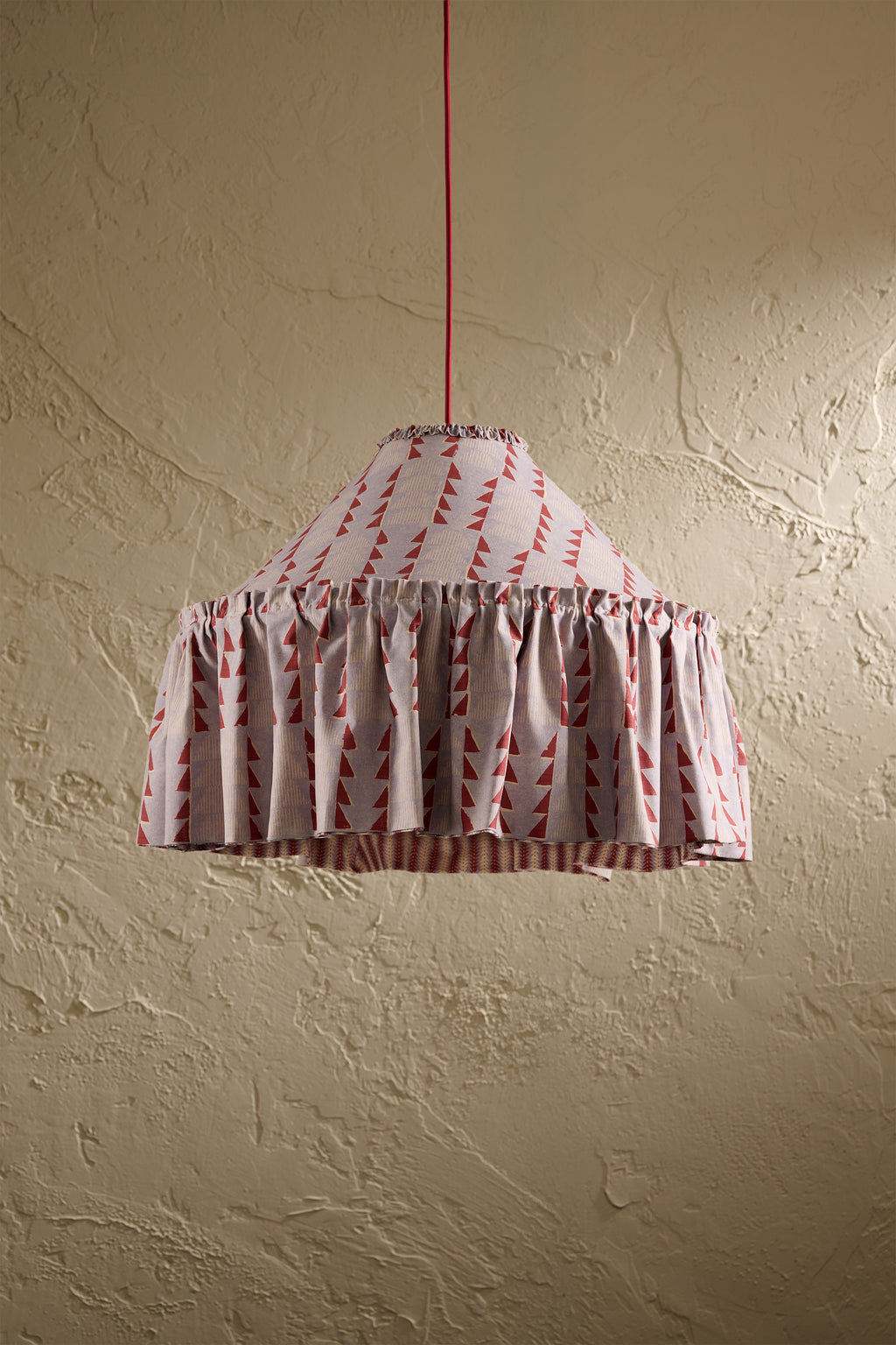 Ellis Ruffle Statement Lampshade in Dusty Blue & Merlot showing the gathered ruffle and contrasting geometric lining hanging in front of a textured wall