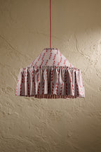 Ellis Ruffle Statement Lampshade in Dusty Blue & Merlot showing the gathered ruffle and contrasting geometric lining hanging in front of a textured wall