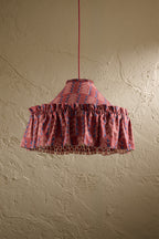 Ellis Ruffle Statement Lampshade in Merlot showing the gathered ruffle and contrasting geometric lining hanging in front of a textured wall