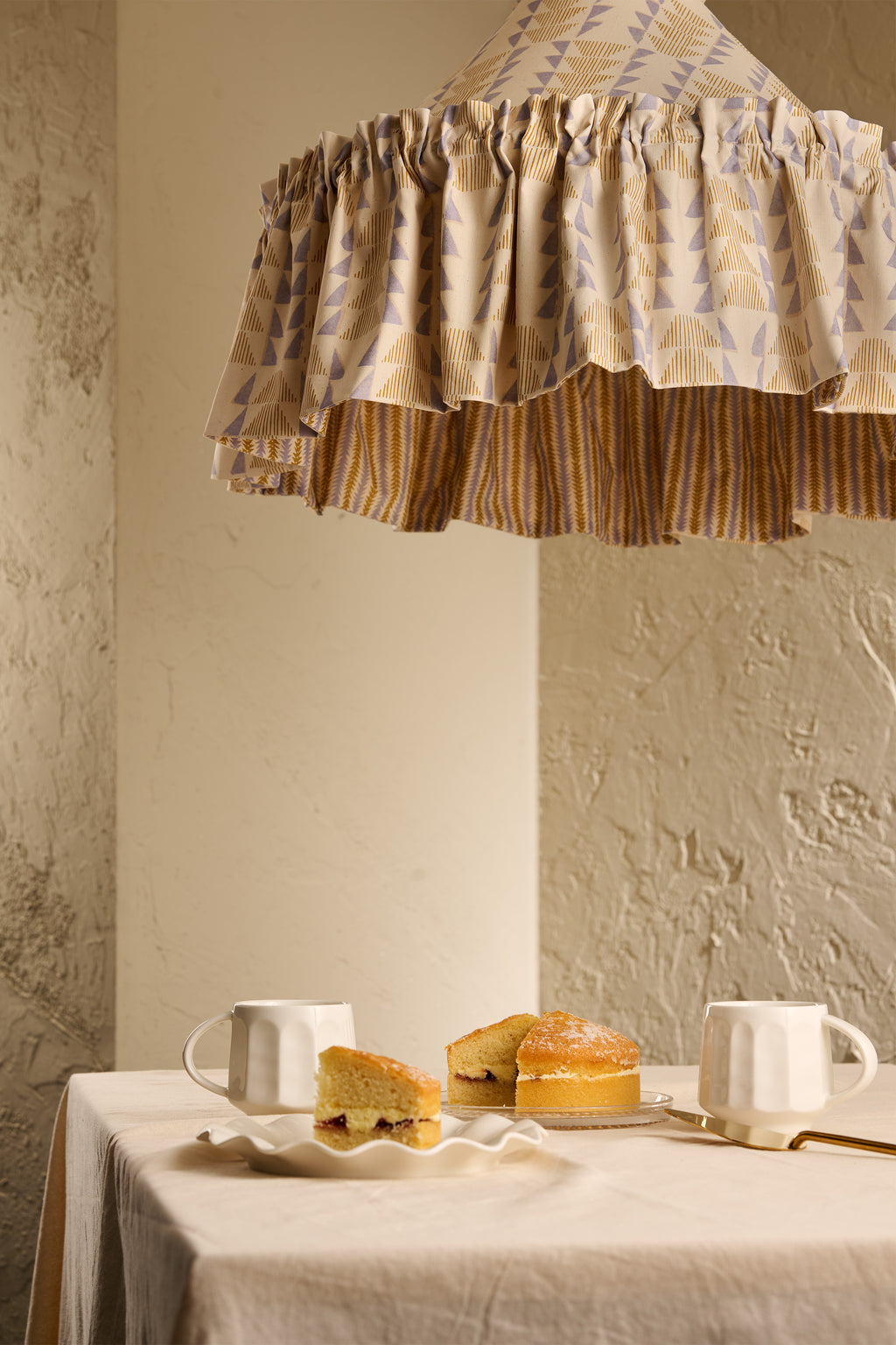 Close-up of Ellis Ruffle Statement Lampshade in Dusty Sky & Ochre showing the gathered ruffle and contrasting geometric lining above a dining table