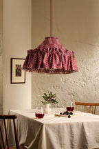 Ellis Ruffle Statement Lampshade in Merlot with contrast printed lining, hanging above a dining table in a warm neutral interior