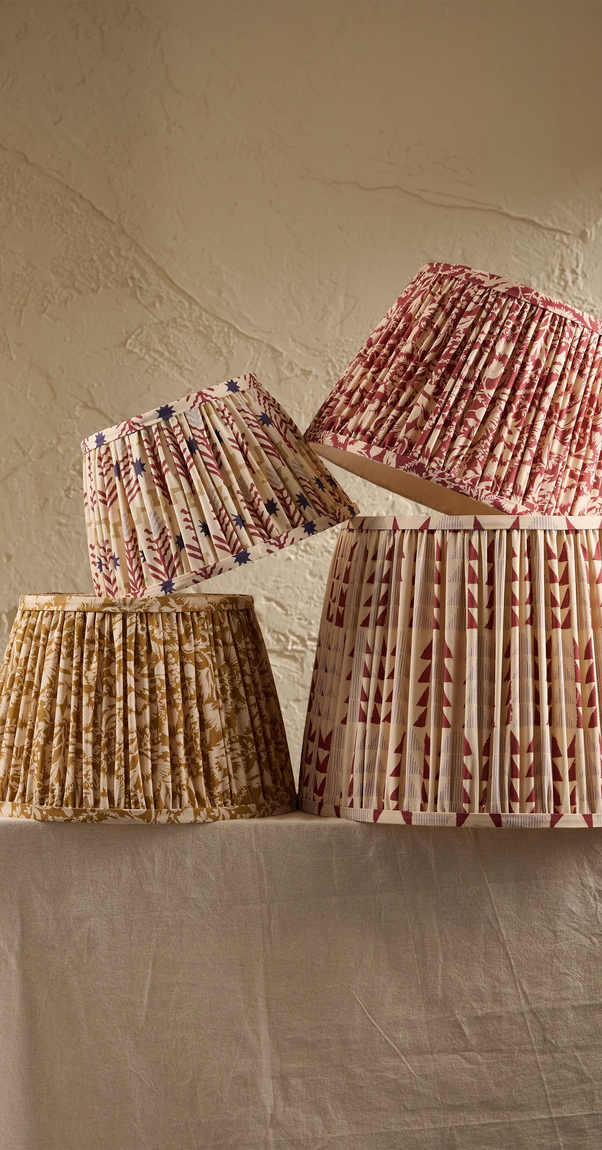 Four pleated to pastures new lampshades in fun patterns sitting on a table with cream linen tablecloth